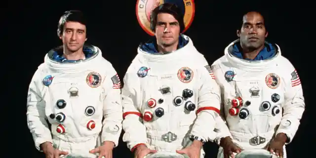 THREE ASTRONAUTS IN FRONT OF THE CAPRICORN ONE LOGO (L-R)-PETER WILLIS(SAM WATERSON),COMMANDER CHARLES BRUBAKER(JAMES BROLIN) AND COMMANDER JOHN WALKER (O.J.SIMPSON) *** Local Caption *** Feature Film
