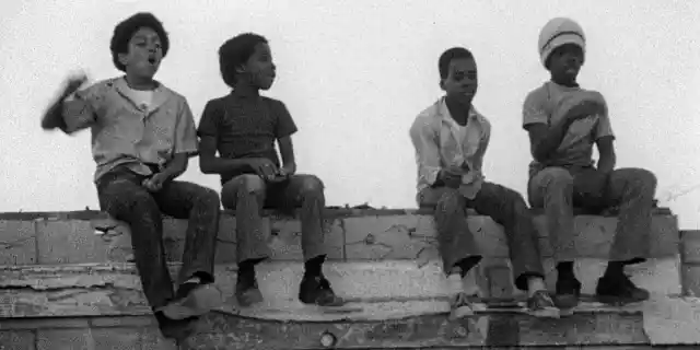 Stan Junior (played by Jack Drummond, left) and friends sitting on wall in Charles Burnett&#039;s KILLER OF SHEEP. Many of the children in the film also participated in the making of the film, helping out with sound and lighting.  Still courtesy of Milestone Films.